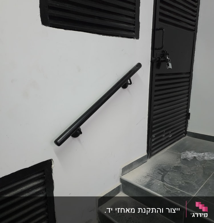 מעקה שחור על קיר לבן ליד מדרגות אפורות